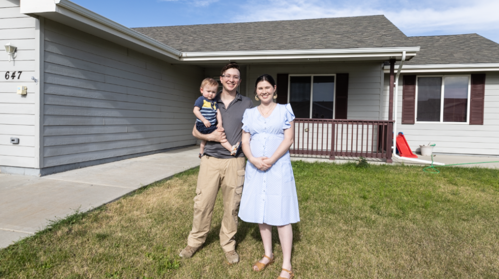 Bodee, his wife Alexandria and their young son proudly stand in front of their first home!
