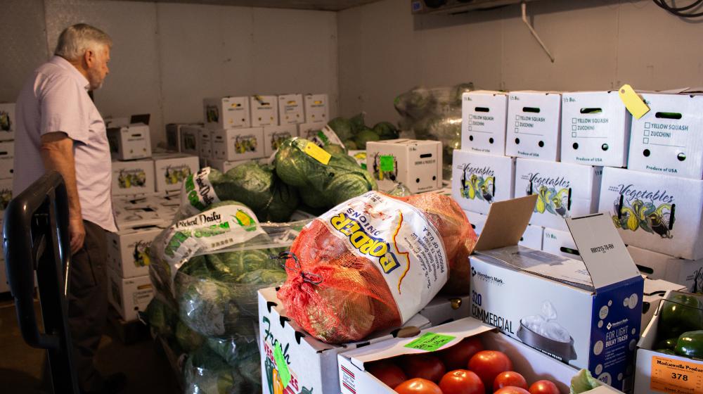 A visitor takes a closer look at produce in a cooler awaiting delivery