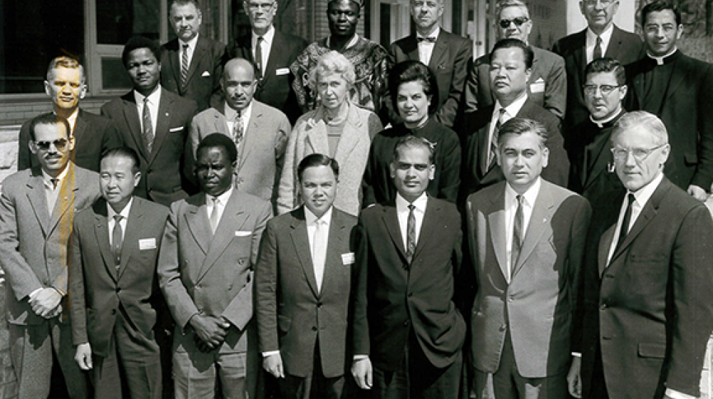 Group of adults in business suits standing on the front steps of a building. They are the 1963 coop seminar graduates of uwcc, the first class ever.