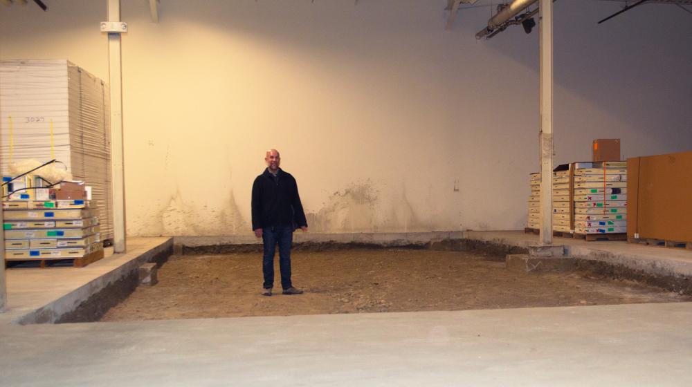 Richard Berkfield of Food Connects stands in a large, shallow square hollow in a cement floor