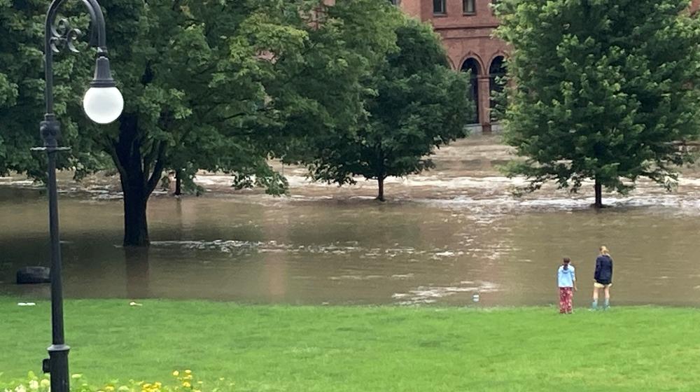  A stunned mother and daughter watch flood waters overtake State Street and the Vermont Capitol lawn