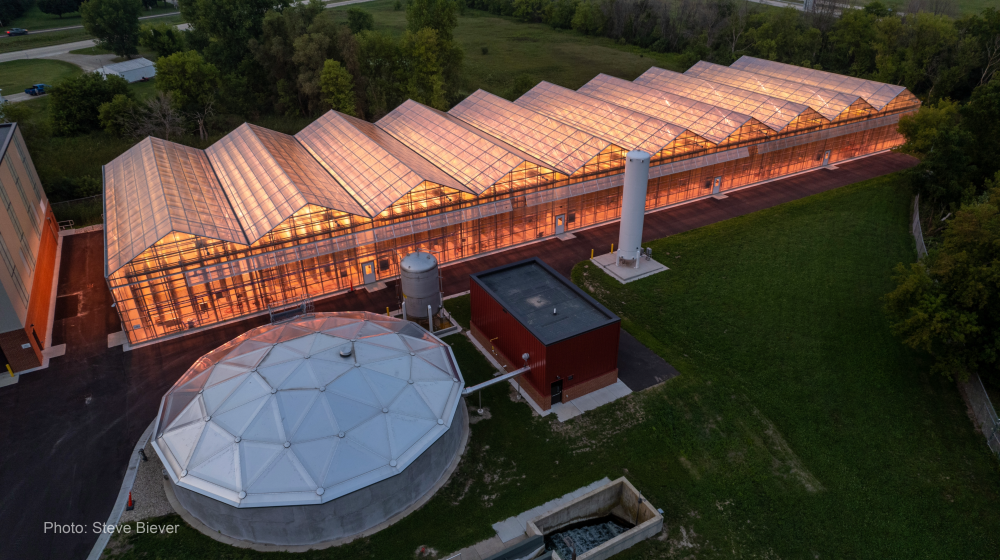 An aerial view of a glowing greenhouse at the Waupun Wastewater Treatment Facility.