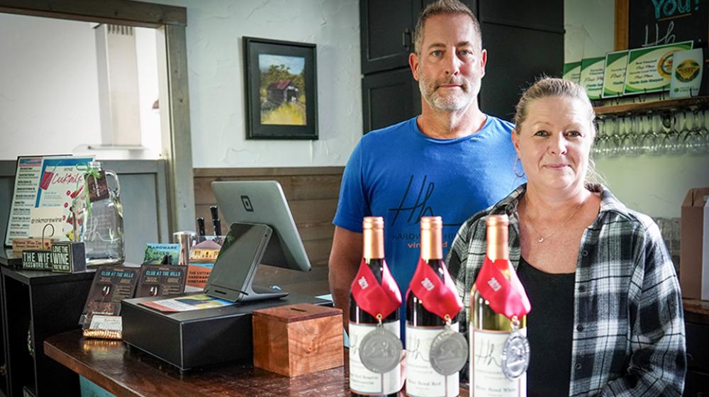 Two people in front of wine bottles