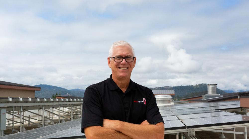 Bruce Hanna, owner of Hampton Inn and Suites Roseburg, visits solar panels recently installed on hotel roof.