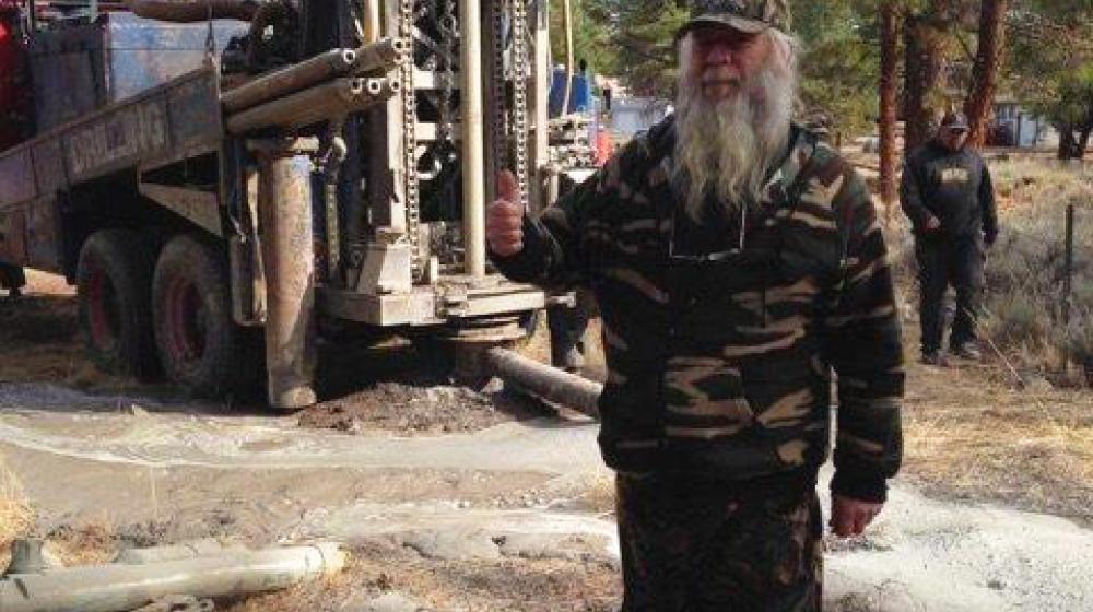 Robert Simon stands in front of his new well in Spalding, California, giving the thumbs up sign. 