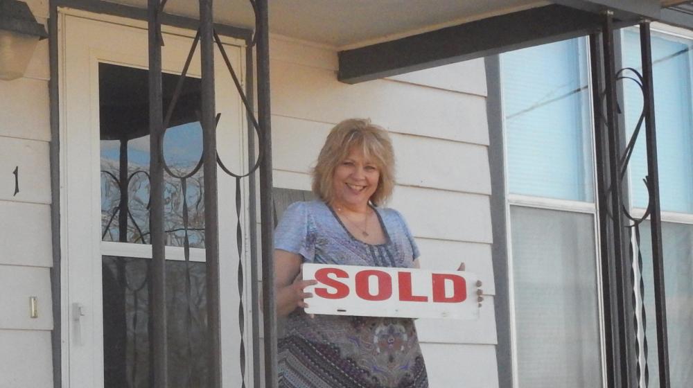 Cindy proudly holds the SOLD sign.