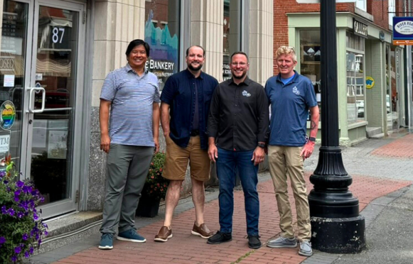 Brian Eng of Sustaine and the three owners of The Bankery and Skowhegan Fleuriste stand on the sidewalk in front of The Bankery with other businesses visible in the background. 