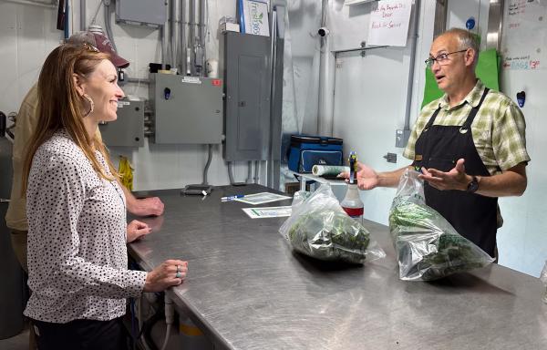 State Director Julia Hnilicka smiles at local business owner Henry Krull as he bags up lettuce and explains hydroponic farming.