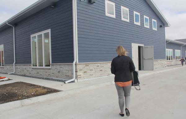 A woman with a bag walks towards the door of a newly built childcare center.