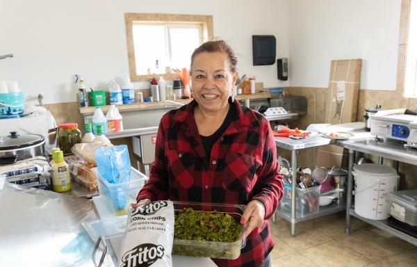 Woman holding green chile in her restaurant kitchen
