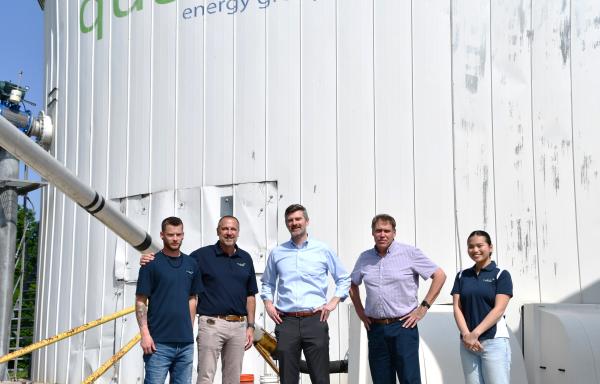 People standing in front of large bio-fertilizer storage tank.