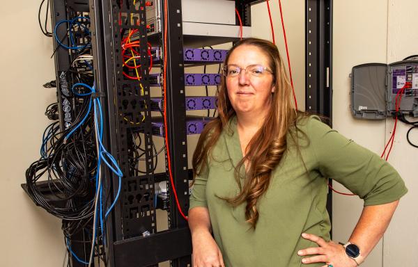 A woman stands in front of an internet service cart, with wires and cables leading to and from ports and the ceiling.