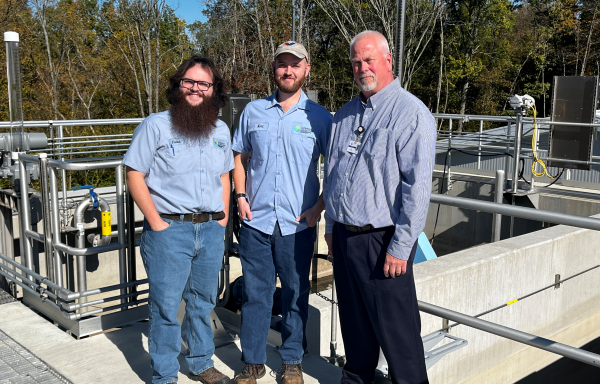 Men standing on top of wastewater plant building. 