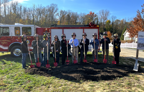 People standing in front of a fire truck in a field. 