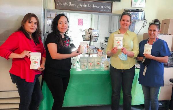Staff from Back Yard Farms hold packages of apple chips that were just produced and ready for sale using the freeze-drying method.