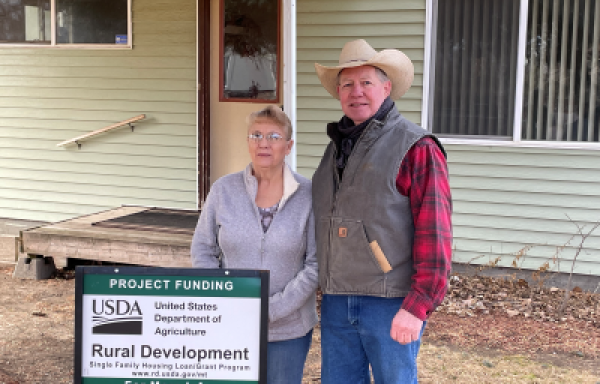 Woman and man standing in front of their home in Montana.