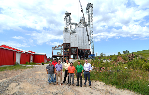 Group standing in front of feed mill under construction