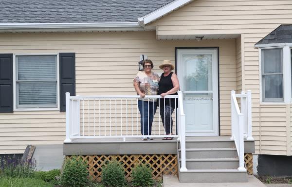 Melanie Bauer Dukart and DIane Wiege pose in front of her home in Hazen, North Dakota.