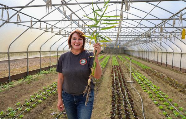Oksana holding a piece of freshly picked ginger in her greenhouse