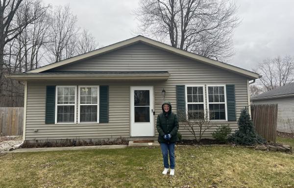 Homeowner stands out front of new home purchased with help from the USDA Single Family Housing Direct Loan program. 
