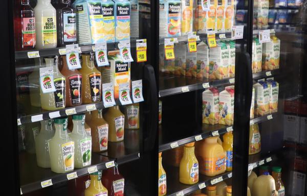 refrigerated section of a grocery store. well lit and has items like orange juice in it.