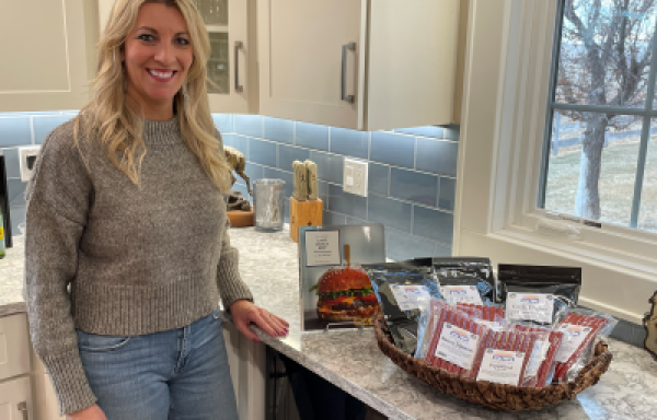 Woman standing in kitchen next to basket of processed meat products