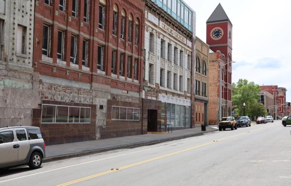 Brick buildings with many windows line a street in Montana. A clock tower is seen in the background.