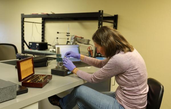 A woman bends over samples in a laboratory environment.