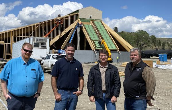 Four men stand in front of a fertilizer production plant under construction in Montana.