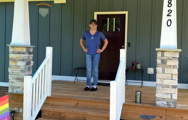 Smiling man standing on porch of his new house.