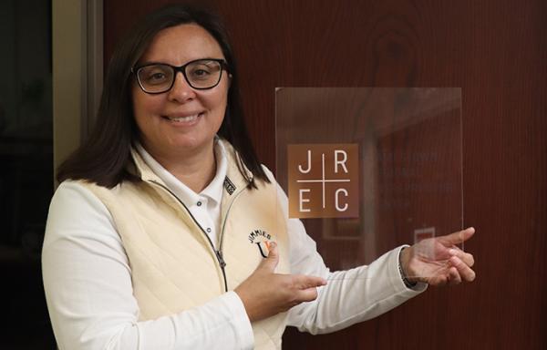 Katherine Roth, executive director of the Jamestown Regional Entrepreneur Center, holds a plaque with the letters "JREC" on it, the abbreviation for her organization.