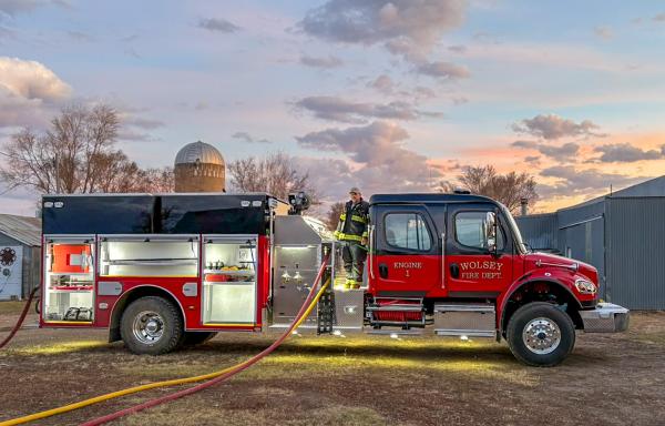 firefighter standing on fire truck at a farm in the evening