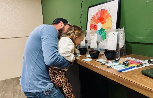 Trey with his daughter looking at coffee grounds