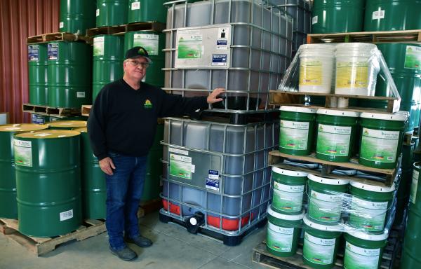 Renewable Lubricants CEO Bill Garmier stands in front of barrels of Lubricant Products