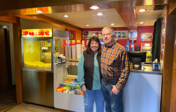 Woman and man standing in front of concession stand at movie theater.