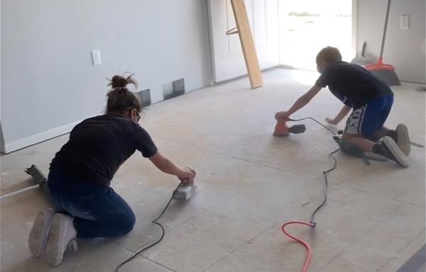 Male and female sanding a floor.