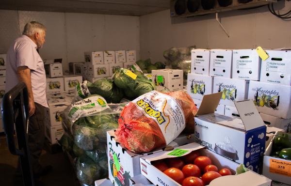 A visitor takes a closer look at produce in a cooler awaiting delivery