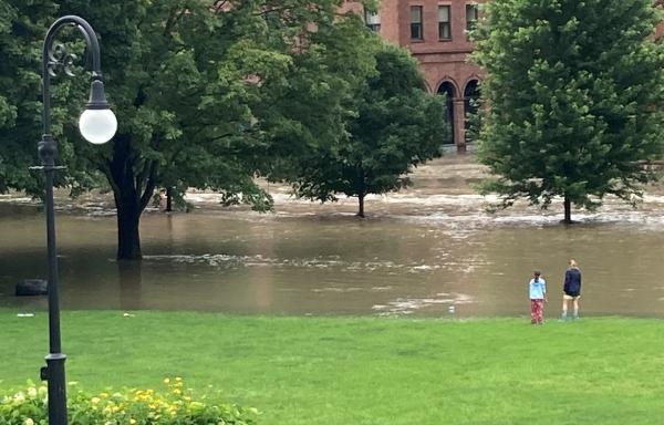 A stunned mother and daughter watch flood waters overtake State Street and the Vermont Capitol lawn