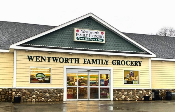 Wentworth Family Grocery is a long, low building with yellow siding, large glass doors, and stone trim around the base of the building. 