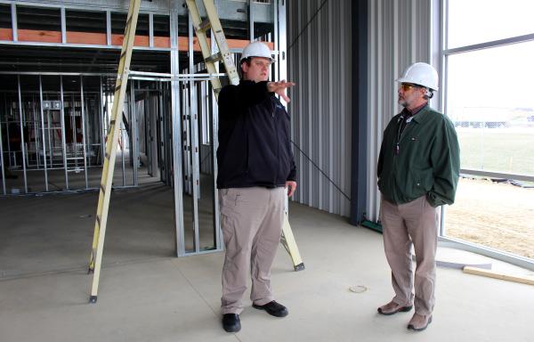 Fixed Base Operations Manager Chris Botkin (left) gives Area 2 Specialist Robert Wilson a tour of the new hangar while it is under construction.