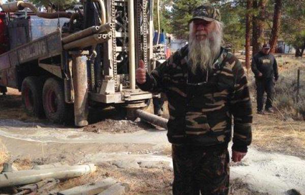 Robert Simon stands in front of his new well in Spalding, California, giving the thumbs up sign. 