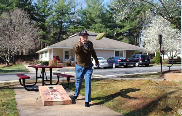 Henry Smith, wearing his World War II uniform coat because he had just had pictures taken in it, plays the lawn game Cornhole at Milnwood Village Apartments in Farmville. 