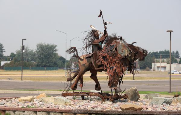 Metal sculpture with parking lot in back 