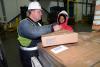 Man & woman workers wearing hardhats and filling out business shipping orders